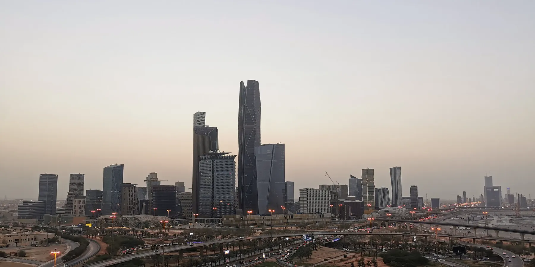 King Abdullah Financial District skyline at dusk above a highway interchange in Riyadh