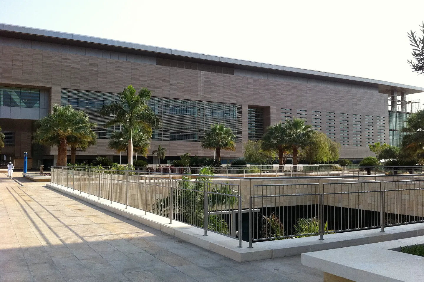 A stone and glass building with palm trees on the KAUST campus