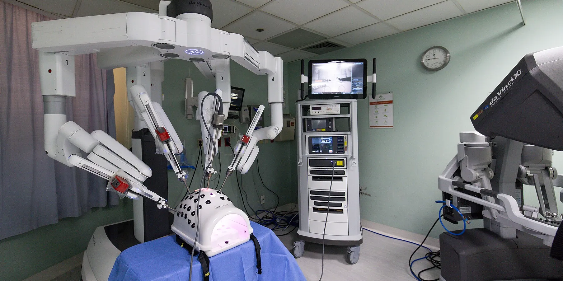 A four-arm robotic surgical system positioned over a training model in an operating theatre
